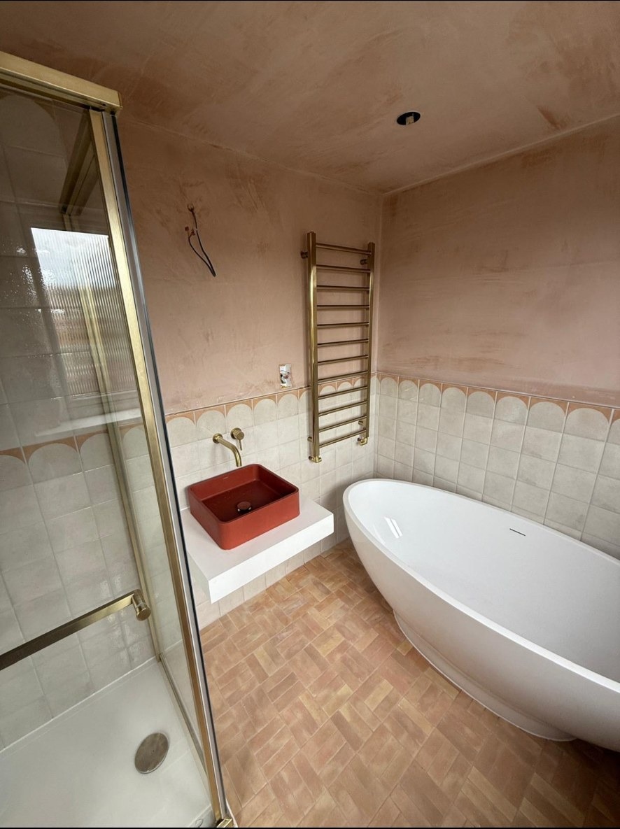 Brushed brass shower fittings against scalloped bathroom tiles on a completed Nexus installation.